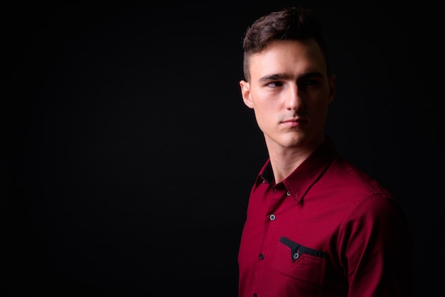 Photo de Studio de jeune homme d'affaires beau en chemise rouge sur fond noir