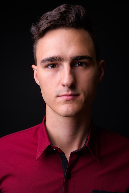 Photo de Studio de jeune homme d'affaires beau en chemise rouge sur fond noir