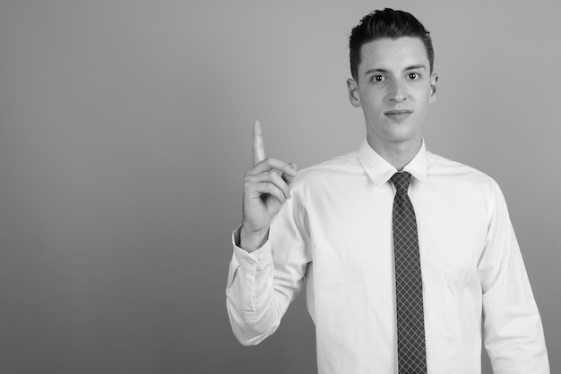 Photo de Studio de jeune homme d'affaires beau portant chemise et cravate sur fond gris en noir et blanc