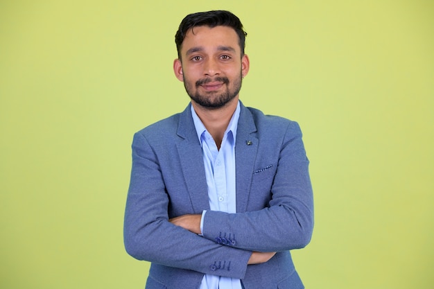 Photo de Studio de jeune homme d'affaires persan barbu beau en costume contre clé chroma avec fond vert