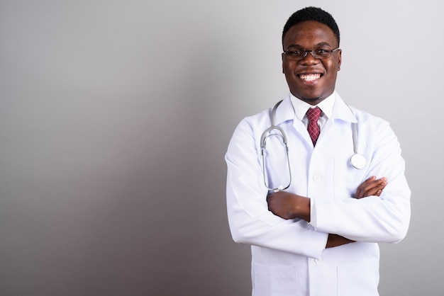 Photo de Studio de jeune homme africain médecin portant des lunettes sur fond blanc