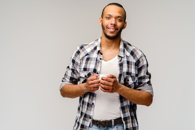 Photo de Studio de jeune homme ayant une tasse de café sur gris clair.