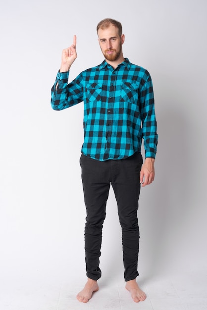 Photo de Studio de jeune homme barbu hipster contre blanc