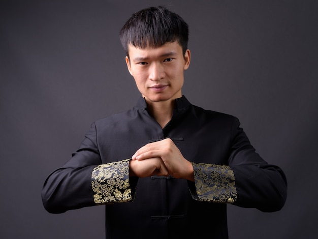 Photo de Studio de jeune homme chinois contre gris