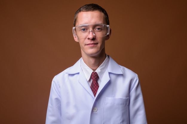 Photo de Studio de jeune homme médecin sur brown