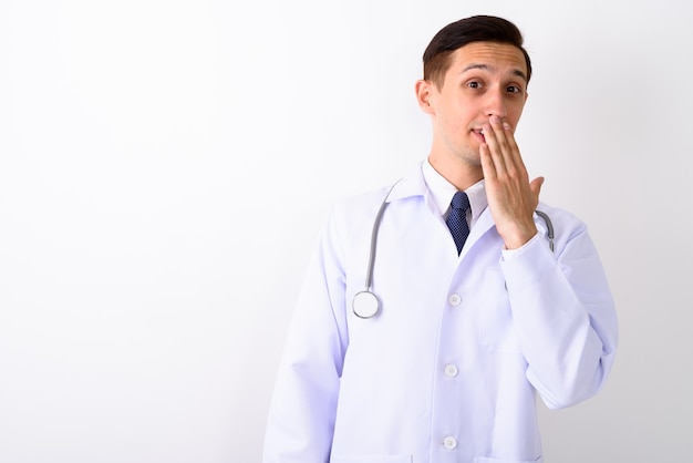 Photo de Studio de jeune médecin bel homme couvrant la bouche avec han