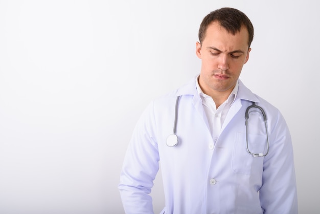 Photo de Studio de jeune médecin homme musclé pensant tout en regardant