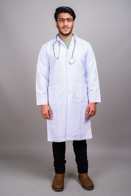 Photo de Studio de jeune médecin indien beau contre gris