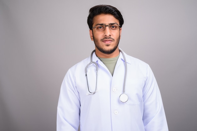 Photo de Studio de jeune médecin indien beau contre gris