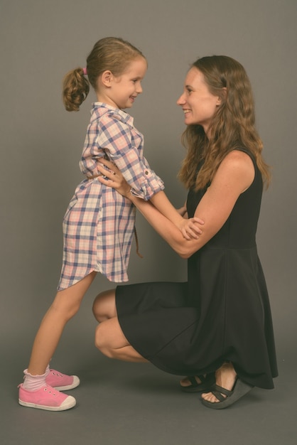 Photo de Studio de mère et fille de liaison ensemble contre un mur gris