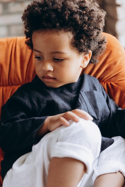 Photo de studio d'un petit garçon à la peau sombre vêtu de vêtements en lin confortables