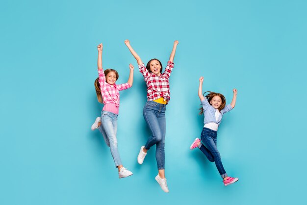 Photo de la taille du corps sur toute la longueur de la famille blanche amicale joyeuse bénéficiant de concours de course pin-up gagnant tout en isolé avec fond bleu portant des jeans denim