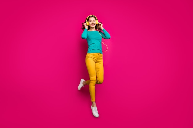 Photo de la taille du corps sur toute la longueur de joyeux positif jolie jolie petite amie charmante mignonne portant un pantalon jaune pantalon blanc chaussures souriant à pleines dents isolé sautant sur fond de couleur rose vif