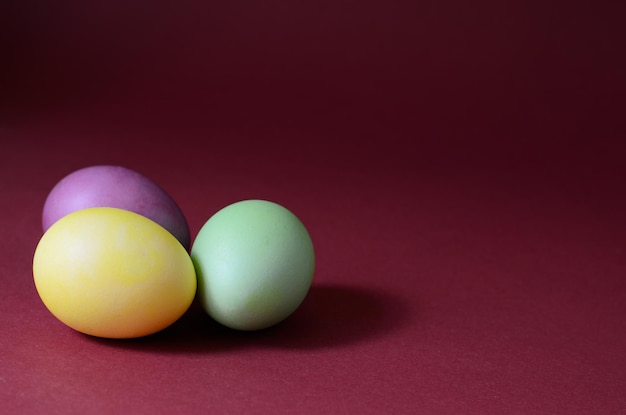 Photo tendance de trois œufs de Pâques multicolores sur fond violet foncé.