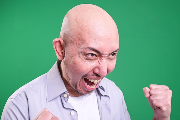 La photo de tête d'un homme chauve qui crie en colère et le visage en colère d'un hommes chauve asiatique