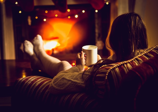 Photo tonique d'une femme se réchauffant avec du thé chaud au foyer en hiver