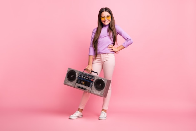 Photo de tout le corps d'une petite fille hipster tenir boom box porter un pantalon de cavalier violet isolé sur fond de couleur pastel