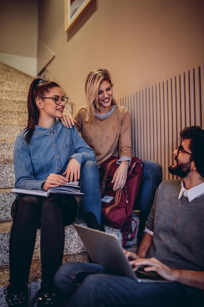 Photo de trois étudiants assis dans un escalier et étudiant