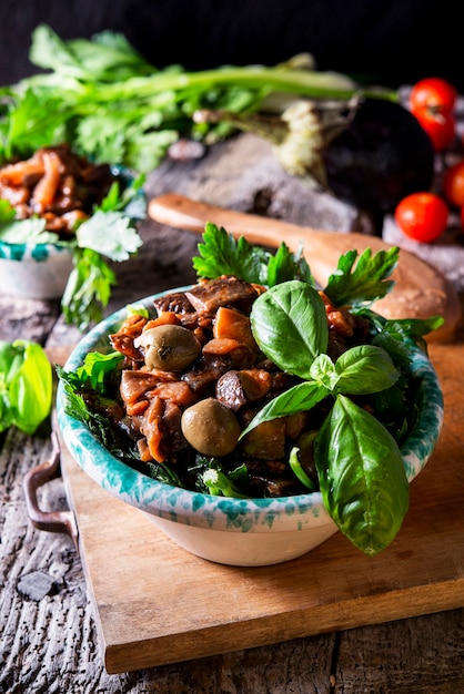 Photo photo verticale d'une caponata d'aubergine, ypical salade sicilienne image alimentaire sombre rustique