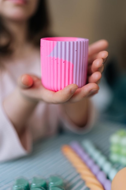 Une photo verticale coupée d'une artisanne méconnaissable tenant un moule en silicone à la main pour créer