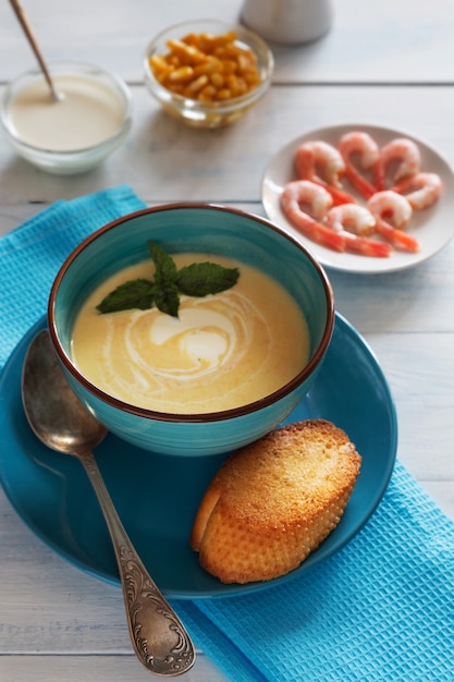 Photo verticale du bol de soupe à la crème avec des crevettes et une cuillère