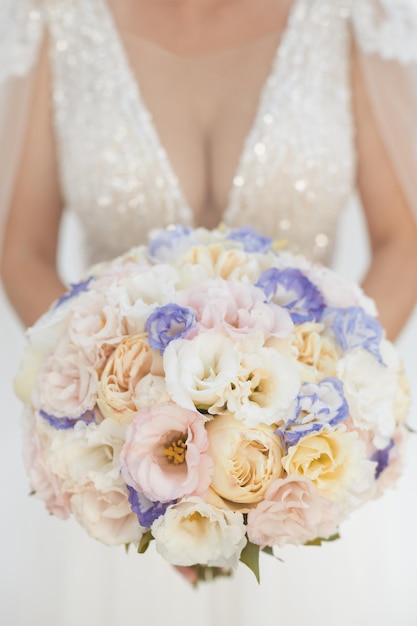 Photo verticale du bouquet de la mariée avec des fleurs de saison aux couleurs blanc, ivoire et violet au mariage