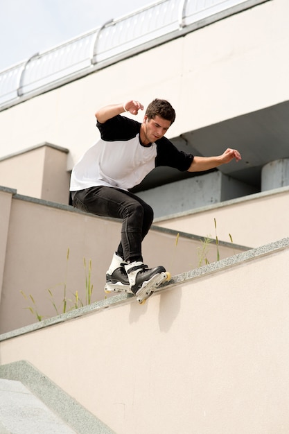 Photo verticale du jeune patineur masculin faisant des cascades à l'extérieur sur la rue. Vue urbaine. Patinage seul Astuces professionnelles. Lumière du jour sur l'été.