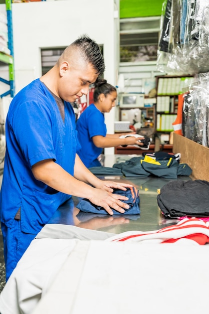 Photo verticale des employés d'un service de blanchisserie pliant des vêtements dans une chambre