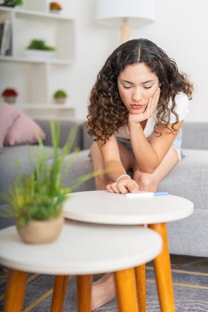 Photo photo verticale d'une femme anxieuse vérifiant les résultats d'un test de grossesse