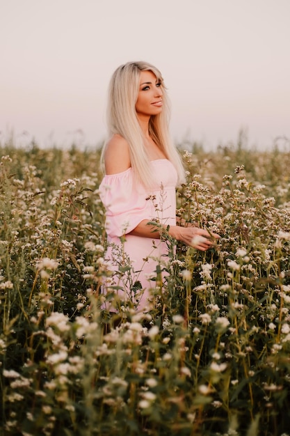 Photo verticale femme blonde posant dans le grand champ sans fin de marguerites en soirée d'été