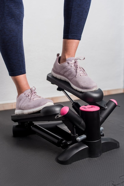 Photo verticale de femme fitness à l'aide de stepper à la maison.