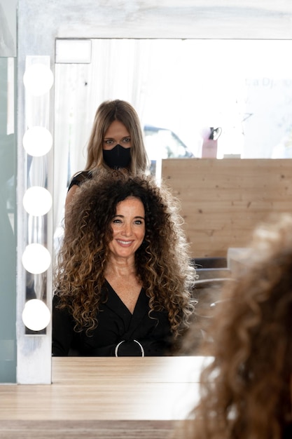 Photo verticale d'une femme mûre et d'un coiffeur devant un miroir