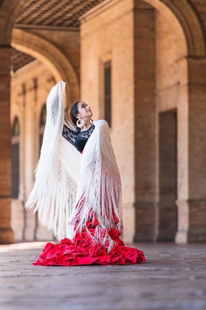 Photo verticale d'une femme en robe de flamenco rouge dansant sur la place d'Espagne à Séville
