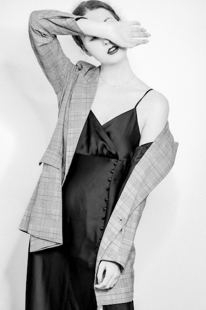 Une photo verticale en gamme de gris d'une femme élégante posant dans une robe et un blazer