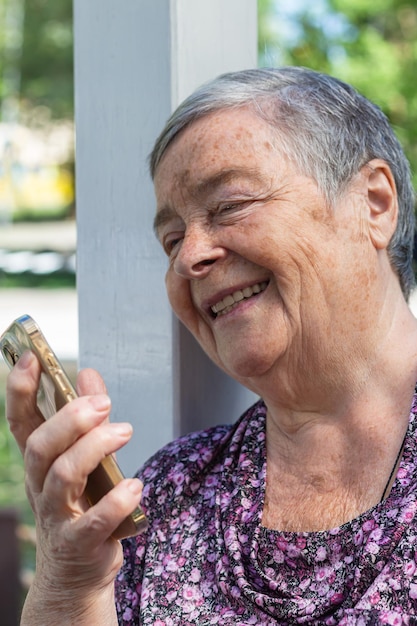 Photo verticale Gros plan portrait d'une femme âgée riante parlant sur un appel mobile mise au point sélective