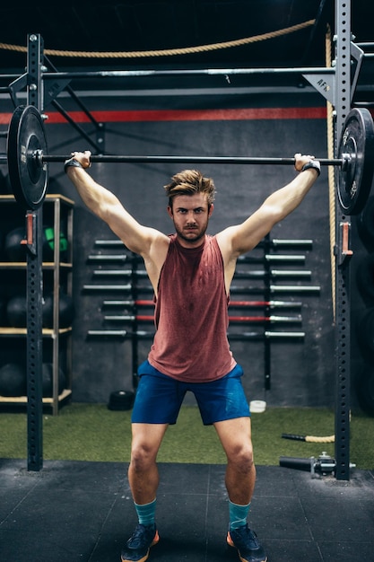 Photo verticale d'un homme soulevant une barre dans une salle de sport