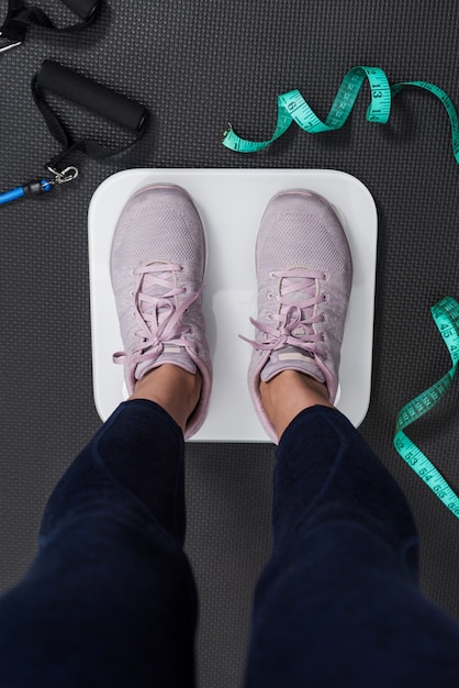 Photo verticale des jambes de la femme sur une échelle électrique pour mesurer ses progrès. Concept de vie minceur et fitness.