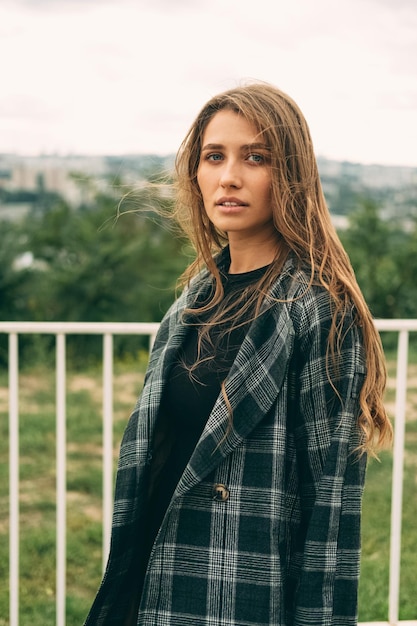 Photo photo verticale d'une jeune femme confiante marchant dehors par une journée venteuse à l'automne ou au printemps