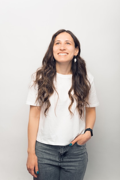 Photo verticale d'une jeune femme souriante et regardant dans un studio blanc.