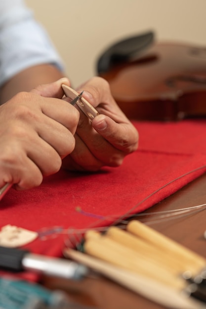 Photo verticale des mains d'un ouvrier réparant un violon dans un atelier