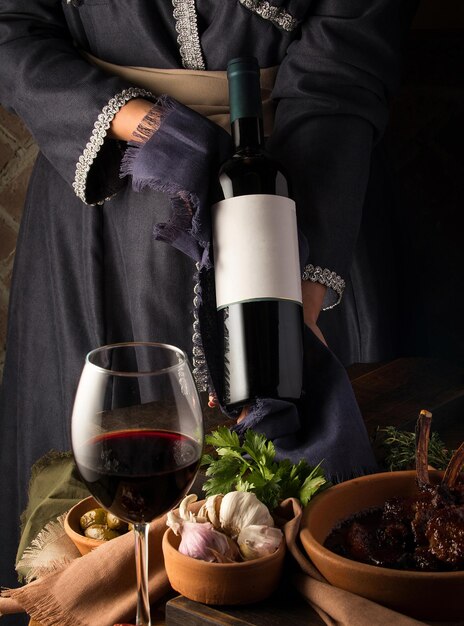 Photo une photo verticale d'une personne en costume traditionnel montrant une bouteille de vin