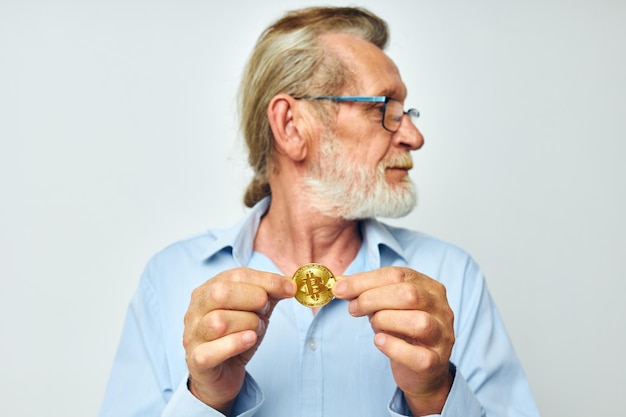 Photo d'un vieil homme à la retraite en chemises bleues bitcoin dans les mains fond clair