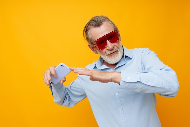 Photo d'un vieil homme à la retraite chemises bleues avec des lunettes prend un arrière-plan isolé selfie