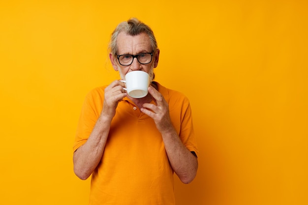 Photo d'un vieil homme à la retraite dans un t-shirt jaune tasse blanche tir monochrome