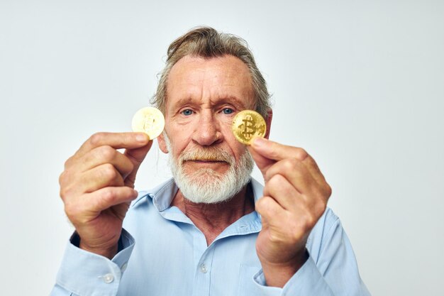Photo d'un vieil homme à la retraite finance des pièces d'or bitcoin près du fond clair du visage