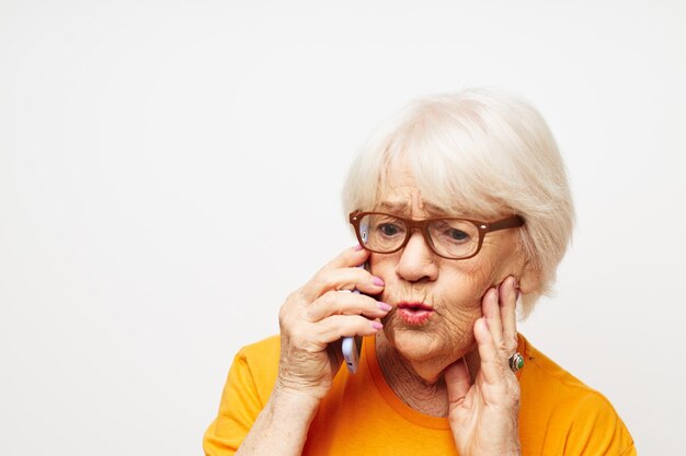 Photo d'une vieille dame à la retraite dans des lunettes à la mode avec un smartphone dans les émotions de gros plan à la main