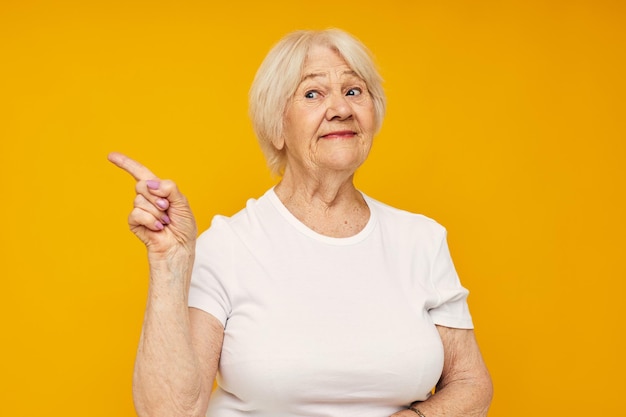 Photo d'une vieille dame à la retraite en t-shirt blanc posant un fond jaune amusant