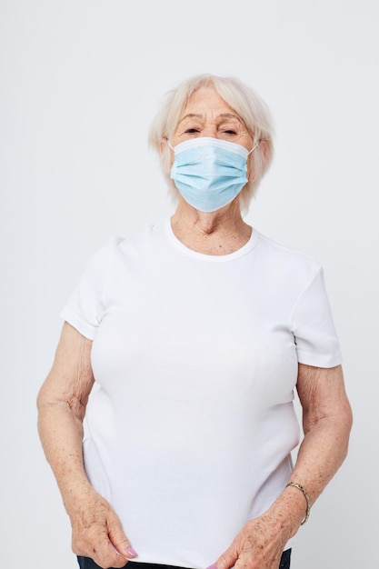 Photo d'une vieille dame à la retraite en t-shirt décontracté et masque médical fond clair