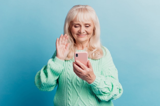 Photo de vieille femme utiliser smartphone vague main bonjour isolé sur fond bleu