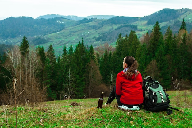 Photo vue arrière de la jeune femme brune avec un sac à dos au sommet des montagnes